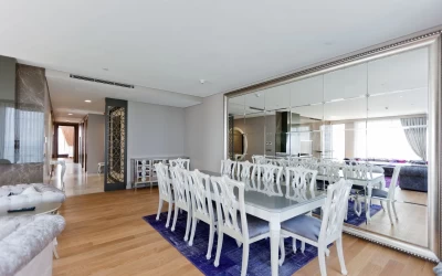 dining-part-of-the-living-room-having-a-white-rectangle-dining-table-and-ten-white-chairs-on-a-sax-blue-carpet