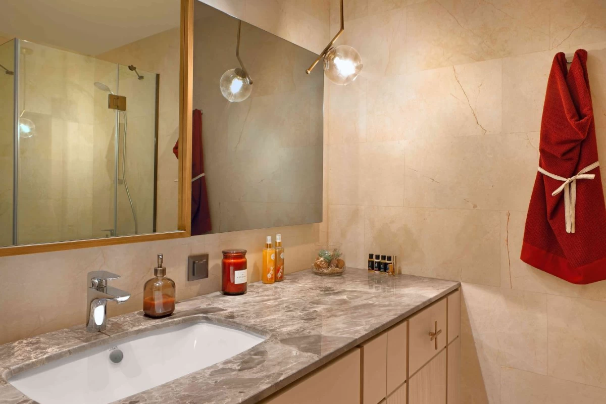 exclusive-bathroom-with-furniture-and-walls-in-beige-shades-with-bath-cabinet-a-mirror-on-it-and-a-red-towel-hung-on-the-wall