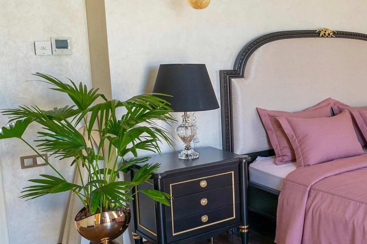 exceptional-bedroom-with-a-bed-pink-cover-on-it-black-nightstand-with-a-black-desk-lamp-a-plant-and-beige-walls