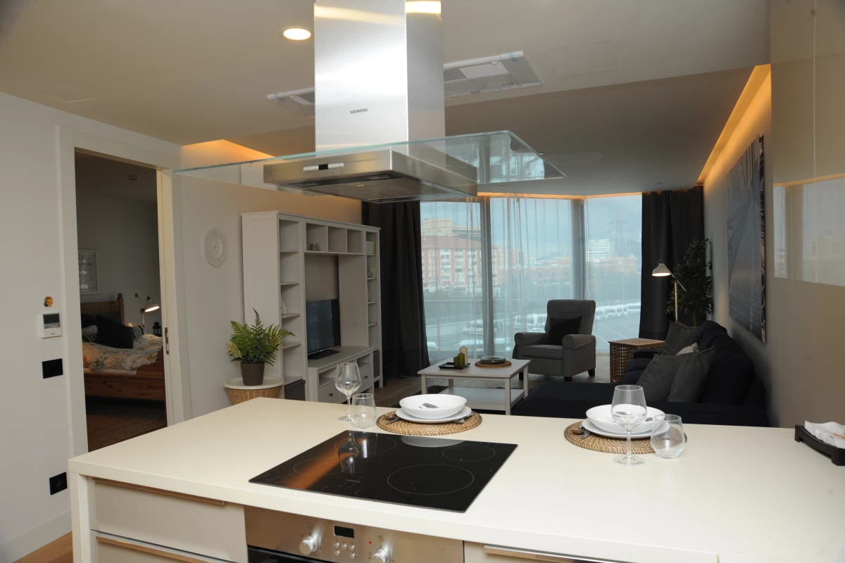 elegant-kitchen-with-white-countertop-built-in-goods-and-pendant-light-in-front-and-living-room-furnished-with-black-and-white-furniture