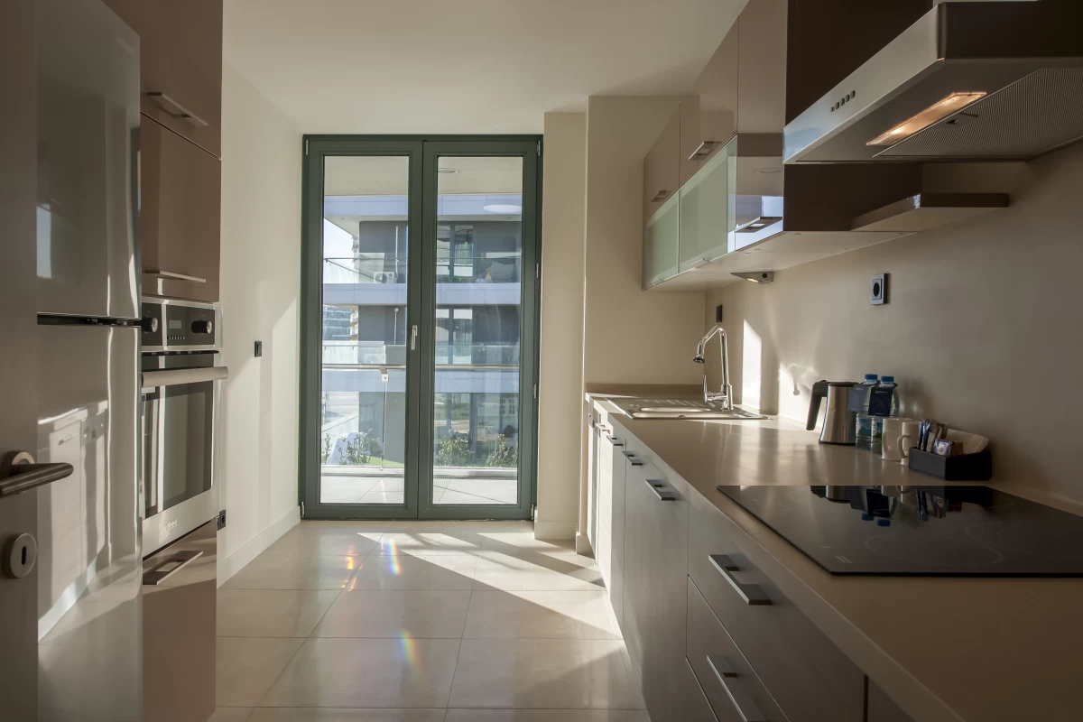 luminous-kitchen-in-minimalist-design-with-furniture-in-beige-shades-comfortable-usage-area-and-window-walls-with-building-view
