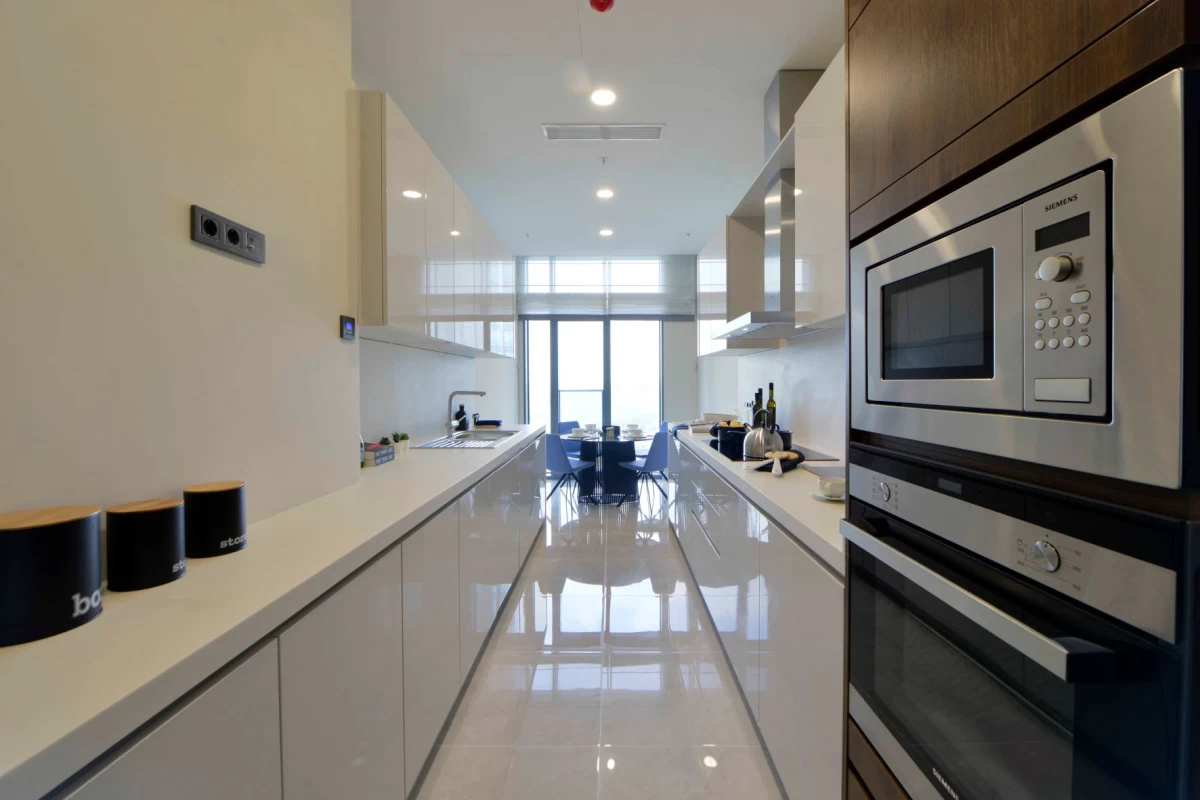 interior-view-of-the-long-and-luminous-kitchen-decorated-with-several-white-cupboards-and-enriched-with-quality-appliances