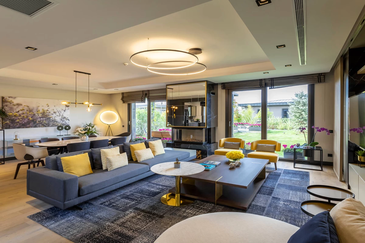 an-upscale-living-room-with-extra-large-usage-areas-blue-sofa-yellow-armchairs-coffee-tables-in-front-tv-unit-dining-table-and-art-pieces