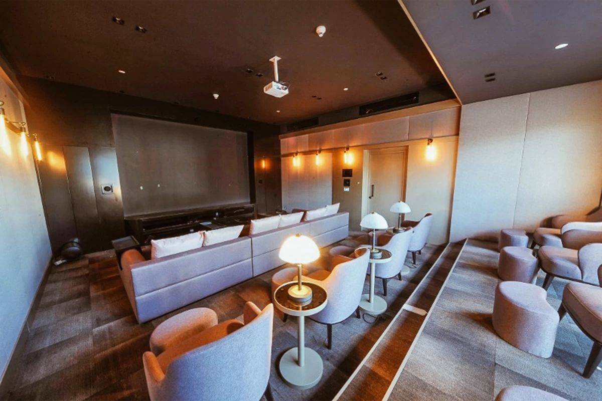 luxurious-movie-theater-of-the-residence-with-comfortable-couches-armchairs-desk-lamps-on-each-desk-and-pouffes-in-front-of-armchairs