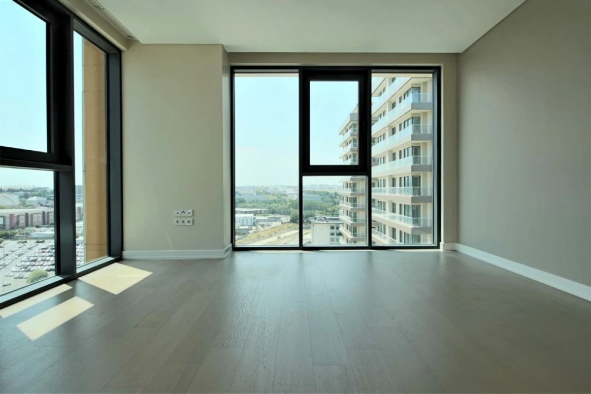 interior-view-of-the-empty-living-room-including-floor-to-ceiling-windows-on-two-facades-with-city-and-neighborhood-view
